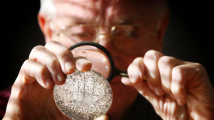 Dr. Chapman (background) views the reverse of the Charlotte Madal with a magnifying class